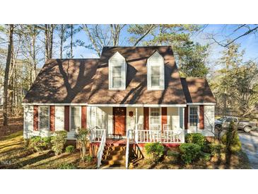 Charming two-story home with red shutters and a welcoming front porch, surrounded by lush landscaping at 1909 Pearces Rd, Zebulon, NC 27597