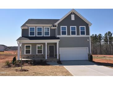 Charming two-story home featuring gray siding, a covered porch, and an attached two-car garage at 25 Calabria Ct, Franklinton, NC 27525