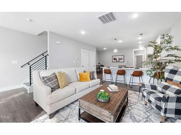 Bright living room featuring a modern sofa, stylish decor, and seamless flow to the kitchen area at 313 E Fourth St, Wendell, NC 27591
