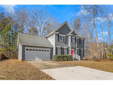 Two-story gray house with a red door, white garage door, and landscaping at 300 Ashwick Dr, Efland, NC 27243