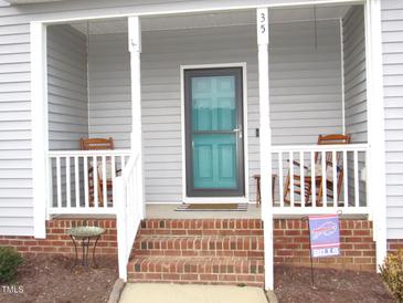 Inviting covered front porch with rocking chairs and brick steps at 35 Meadow Ln, Franklinton, NC 27525