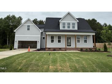 Charming two-story home boasts a welcoming front porch, attached garage, and a lush green lawn at 404 Brodie Rose Landing Way, Smithfield, NC 27577