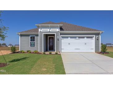 Gray house with white garage doors and landscaping at 104 Barn Door Dr, Lillington, NC 27546