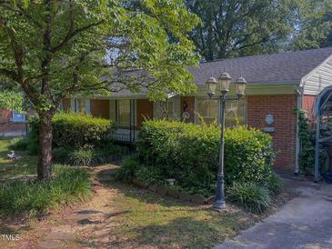 Charming brick home featuring a well-manicured front yard and a vintage lamppost at 2612 Academy St, Sanford, NC 27332