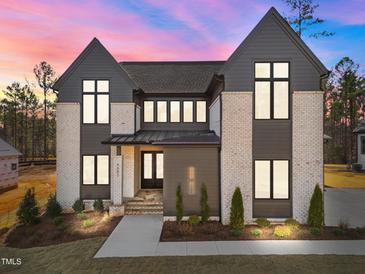 Stunning two-story home featuring a modern design and a combination of brick and siding under a beautiful sunset at 8001 Wexford Waters Ln, Wake Forest, NC 27587