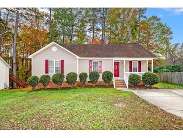 Tan house with red shutters, landscaping, and a red front door at 125 Havencrest Lndg, Garner, NC 27529