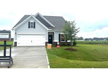 Charming single-Gathering home featuring a well-manicured lawn, attached garage, and neutral exterior at 14 E American Marigold Dr # 65, Benson, NC 27504