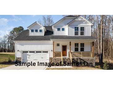 Two-story white house with stone accents, double garage, and a covered porch at 165 Tuskeegee Dr, Smithfield, NC 27577