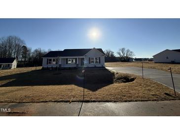 Newly constructed home with a gray exterior, landscaped yard, and driveway at 90 Faucette Dr, Selma, NC 27576