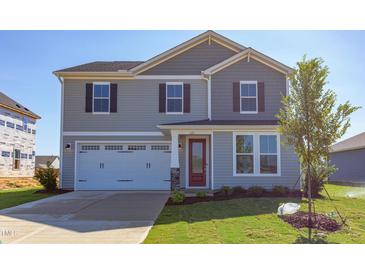 Two-story house with gray siding, white garage door, and red front door at 121 Barn Door Dr, Lillington, NC 27546