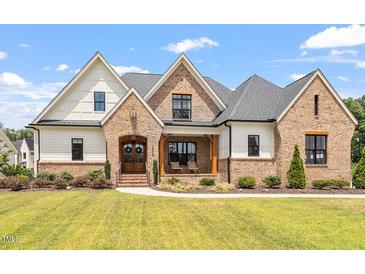 Brick and siding two-story home with a covered porch and manicured lawn at 1505 Montvale Grant Way, Cary, NC 27519