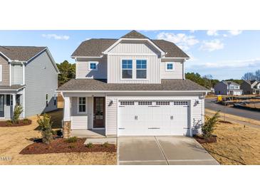 Two-story house with a white exterior, two-car garage, and landscaping at 20 Windflower Ct, Clayton, NC 27520