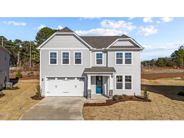 Two-story house with gray siding, white garage door, and a teal front door at 34 Windflower Ct, Clayton, NC 27520