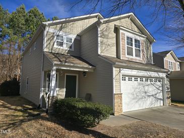 Two-story house with beige siding, a two-car garage, and landscaping at 401 Ganyard Farm Way, Durham, NC 27703