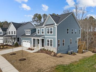 A beautiful two-story home boasts blue siding, stone accents, a two-car garage, and a well-manicured lawn at 645 Silvercomet Dr, Knightdale, NC 27545