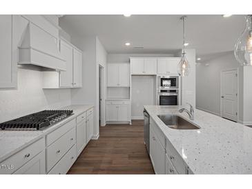 Modern kitchen featuring white cabinets, granite counters, stainless steel appliances, and a gas cooktop at 18 Fairwinds Drive Dr, Lillington, NC 27546