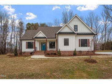 Two-story farmhouse with white siding, brown accents, and a teal door at 195 Daniel Ridge Ln, Roxboro, NC 27574