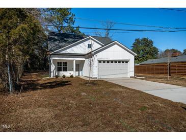 Charming white home featuring a well-manicured lawn and attached garage, set beneath a clear blue sky at 404 Andrews Rd, Durham, NC 27705