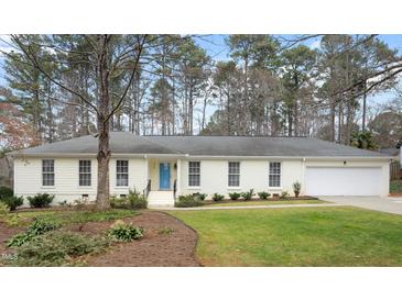 Ranch style home with a white brick facade, attached garage, and manicured lawn at 908 Glen Eden Dr, Raleigh, NC 27612
