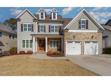 Two-story home with stone accents, a three-car garage, and landscaping at 305 Melvin Jackson Dr, Cary, NC 27519