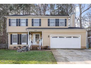 Two-story house featuring a beige exterior, a two-car garage, and landscaping at 6329 Dry Fork Ln, Raleigh, NC 27617