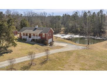 Aerial view of charming red house with pond and wooded area at 8437 Charlie Stovall Rd, Oxford, NC 27565