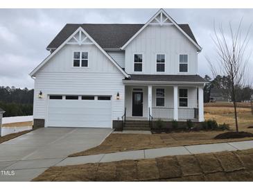 Two-story farmhouse-style home with white siding, a black door, and a two-car garage at 1013 Prominence Dr., Homesite 22, Durham, NC 27712