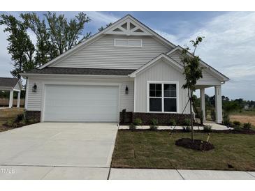 Charming home featuring a two-car garage, manicured lawn, and classic architectural details under a blue sky at 134 Oban Dr, Homesite 133, Sanford, NC 27330