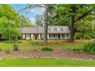 Inviting single-Gathering home featuring a manicured lawn, covered porch, and classic American flag at 1741 W Blackman Rd, Dunn, NC 28334
