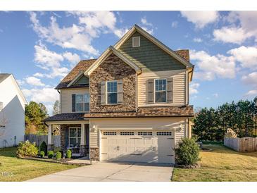 Charming two-story home with a mix of stone and siding, well-manicured lawn, and an attached two-car garage at 2407 Cattail Pond Dr, Zebulon, NC 27597