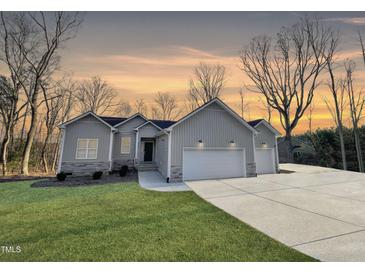 Beautiful single-story home with three-car garage, manicured lawn, and attractive gray siding in a natural setting at 620 Rollins Mill Rd, Holly Springs, NC 27540