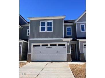 Gray two-story townhome with white garage door and landscaping at 8949 Kennebec Crossing Dr # 52, Angier, NC 27501