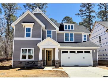 Charming two-story home with a blend of gray siding, stone accents, and a white garage door at 9164 Dupree Meadow Dr # 14, Angier, NC 27501