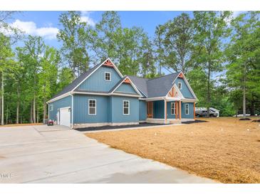 Charming blue two-story home with landscaped yard and a concrete driveway leading to an attached garage at 260 Ellington Rd, Graham, NC 27253