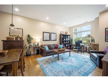 Bright living room featuring a leather sofa, wood furniture, and a blue area rug for a cozy, inviting atmosphere at 317 W Morgan Street # 405, Raleigh, NC 27601