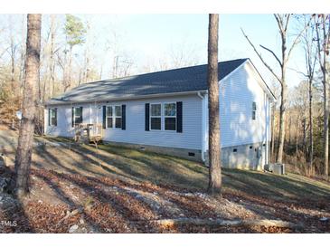 Charming single-story home featuring light siding, black shutters, and a cozy front porch nestled among the trees at 979 Natchez Trce, Fuquay Varina, NC 27526