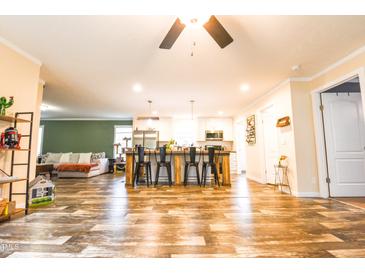 Spacious open-concept living area with a modern kitchen island and wood-look vinyl flooring at 979 Natchez Trce, Fuquay Varina, NC 27526