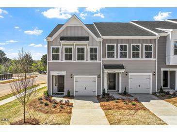 Townhome exterior displaying gray siding, a single car garage, landscaped front yard, and private driveway at 103 Central Townes Way # 297, Raleigh, NC 27603