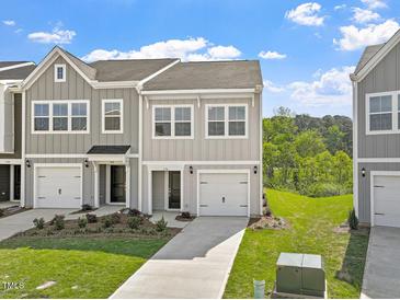 Charming townhome with gray siding, a one-car garage, and a well-manicured lawn and landscaping at 136 Fideaux Blvd # 253, Raleigh, NC 27603