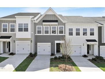 Townhome exterior featuring multi-car garage, well-manicured lawn, and neutral color palette at 152 Fideaux Blvd # 249, Raleigh, NC 27603