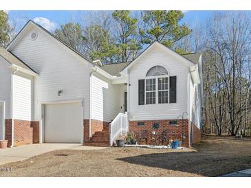 Brick and white exterior home with a two-car garage and landscaping at 3018 E Cotton Gin Dr, Clayton, NC 27527