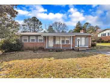 Brick ranch home with gray trim, covered porch, and well-maintained lawn at 704 Sunnybrook Rd, Raleigh, NC 27610