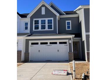 Two-story home with gray siding, white garage doors, and a landscaped yard at 8947 Kennebec Crossing Dr # 53, Angier, NC 27501