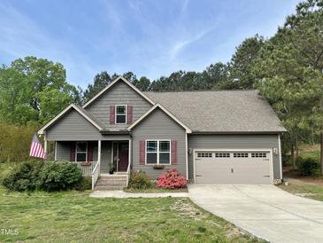 Charming home with a two-car garage, landscaped front yard, and inviting front porch at 100 Churchill Rd, Louisburg, NC 27549