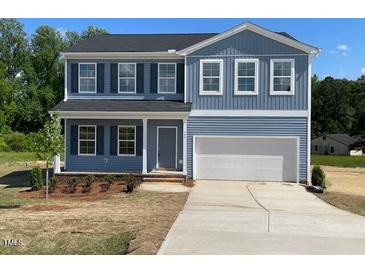 Charming two-story home featuring blue siding, a two-car garage, and a well-maintained front yard at 157 Grove Township Way, Angier, NC 27501