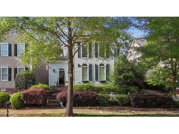 Charming two-story home featuring arched windows, shutters, and lush landscaping at 1703 Happiness Hill Ln, Raleigh, NC 27614