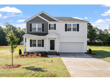 Charming two-story home with a well-manicured lawn, black shutters and a spacious two-car garage at 173 Grove Township Way, Angier, NC 27501