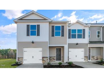 Two-story townhome with gray siding, white garage doors, and landscaping at 426 Honeycutt Oaks Dr, Angier, NC 27501