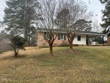 Cozy brick home featuring a covered carport, and a well-maintained lawn at 494 S Mason St, Coats, NC 27521