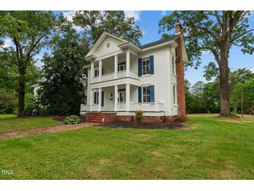Two-story white house with blue shutters, wraparound porch, and landscaped lawn at 309 Hawkins Ave, Sanford, NC 27330